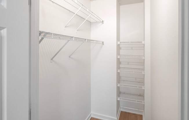 a walk in closet with white walls and shelves and a mirrored closet door