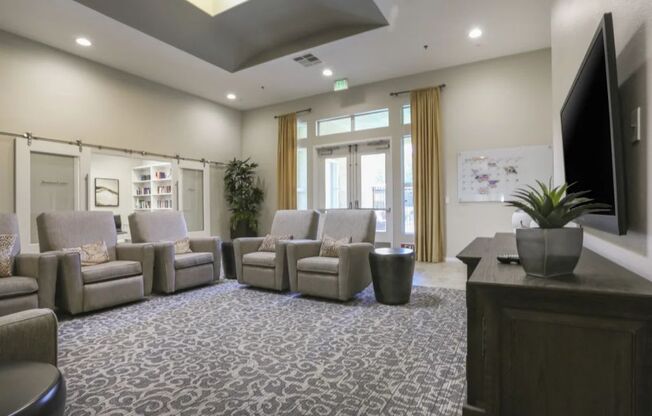 a room with couches and chairs and a tv on the wall  at Tesoro Senior Apartments, Porter Ranch