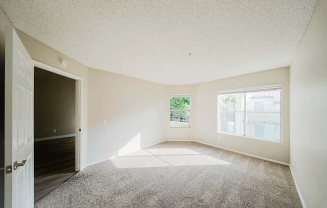 A room with a carpeted floor and a door leading to another room.