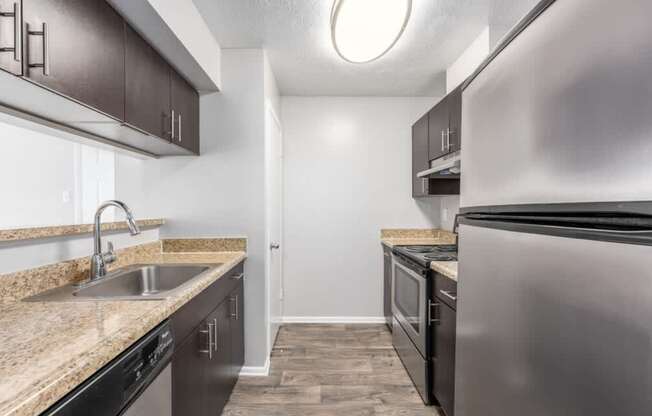 A kitchen with a sink, stove, and refrigerator.