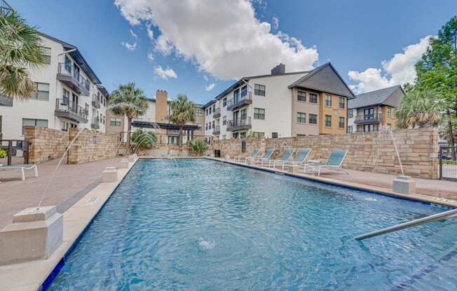 Resort style pool with lounge chairs and palms at Vue Live Oak Apartments, Dallas, 75204