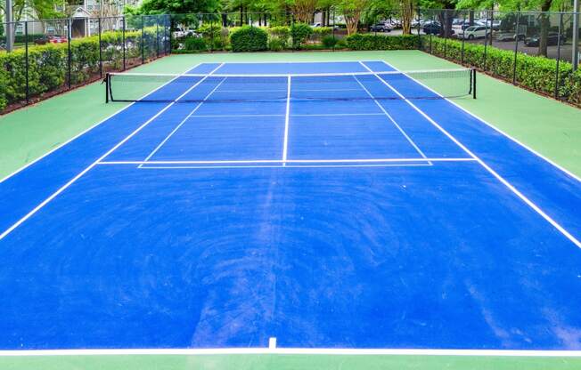 a blue tennis court on a green court