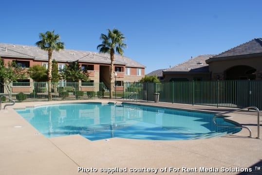 A swimming pool in front of a building with palm trees.