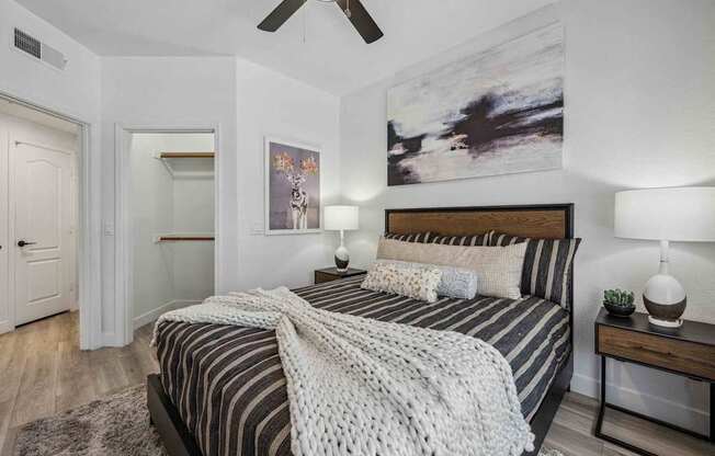 A bedroom with a bed, two lamps, and a painting on the wall. at Lazo Apartment Homes, Arizona
