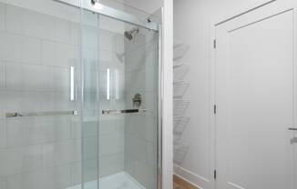 a shower with a glass door in a white bathroom