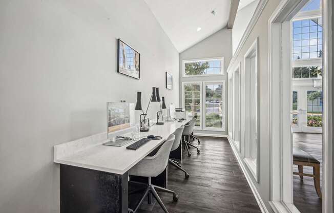 A white desk with a computer and a chair in front of a window.