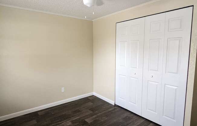 an empty bedroom with a ceiling fan and a closet