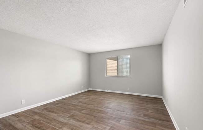 A room with wooden flooring and a window with blinds.