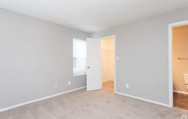 an empty room with a door to a bathroom and a closet