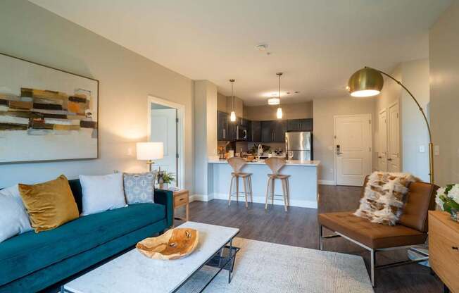 An inviting open-concept living area featuring a modern couch, coffee table, and decor, leading to a stylish kitchen.