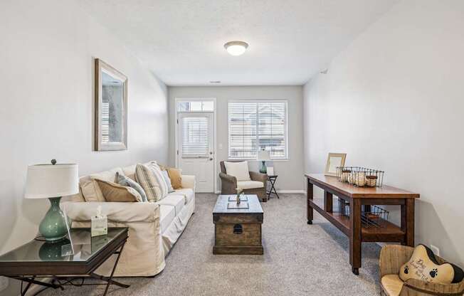 A living room with a white couch, a coffee table, and a chair.