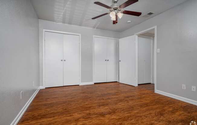 an empty room with a ceiling fan and white closets