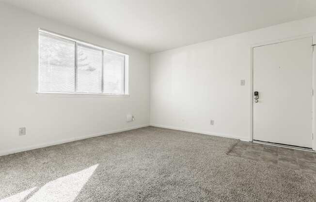 an empty living room with a door and a window