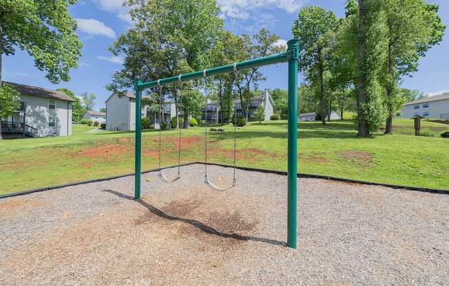 a swing set in a park with houses and trees