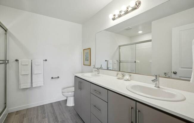 a white bathroom with two sinks and a toilet
