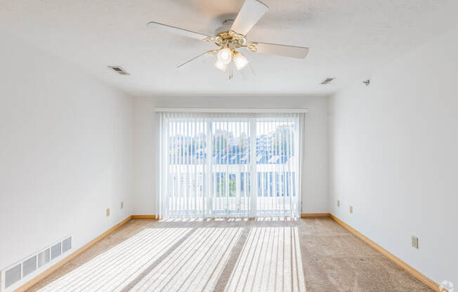 A room with a ceiling fan and a carpeted floor.