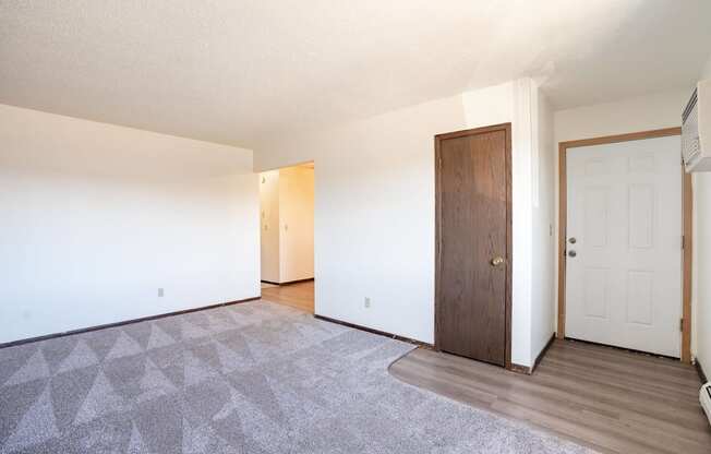 A room with a carpet and a brown door. West Fargo, ND Parkwest Gardens