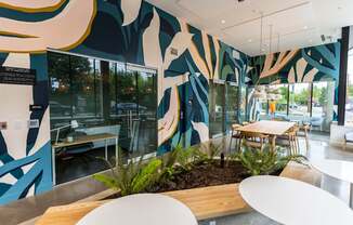 a communal area with tables and chairs and a large mural on the wall