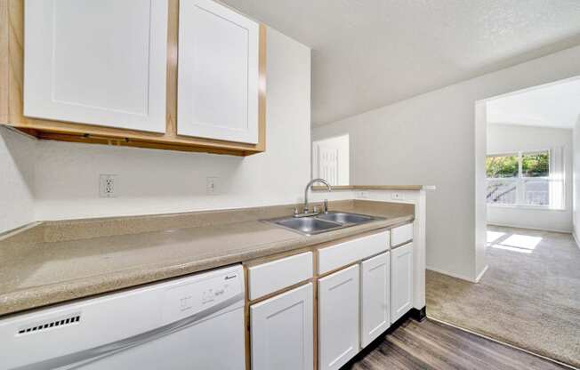 an empty kitchen with white cabinets and a sink