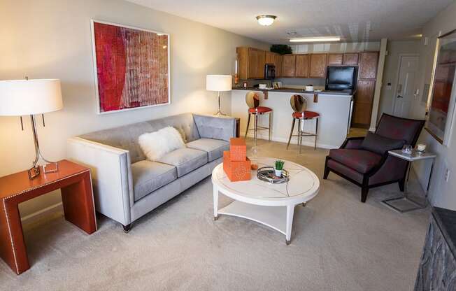 A living room with a grey couch, a white coffee table, and a red lamp.