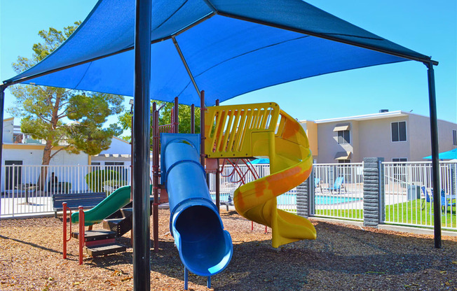 a playground with a blue umbrella and a slide