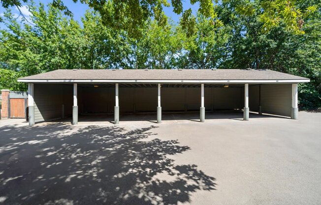 A large building with a grey roof and pillars is surrounded by trees. at Somerset Oaks Apartment Homes, Olathe 66062