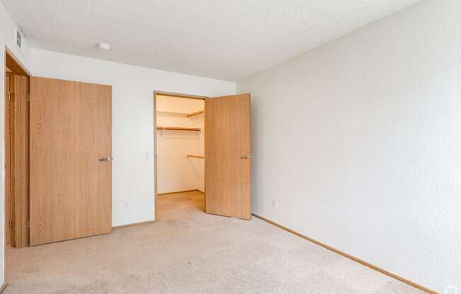 an empty bedroom with a closet and an open door