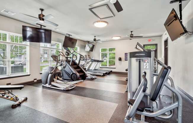 a gym with cardio machines and a tv on the wall