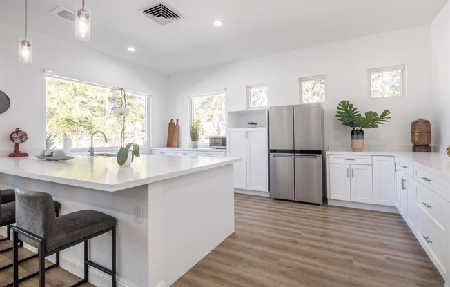 a large white kitchen with white cabinets and a stainless steel refrigerator