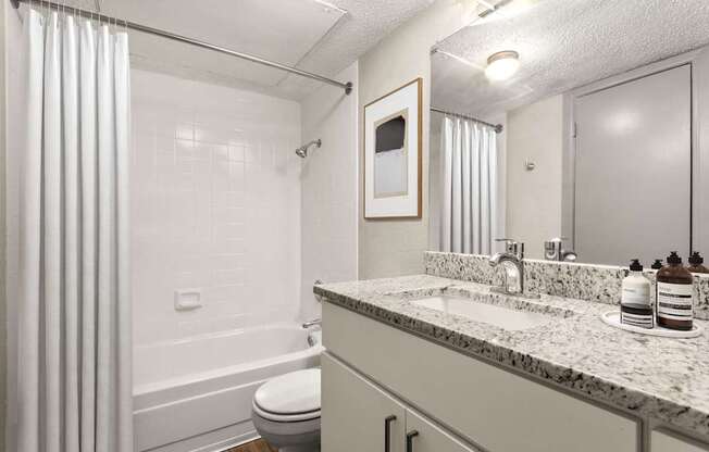 A white bathroom with a toilet, sink, and shower.