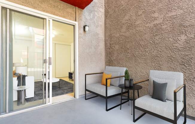 a patio with chairs and a table and a sliding glass door