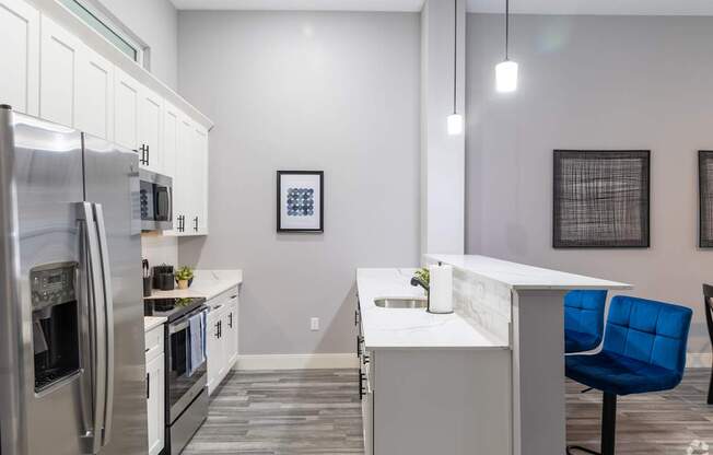 A modern kitchen with a blue chair and stainless steel appliances.