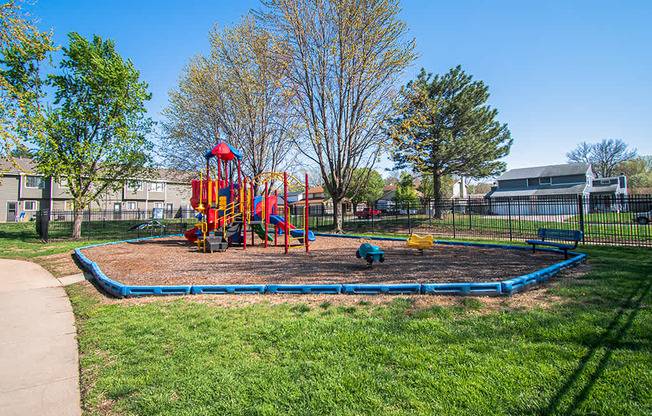 A playground with a blue rubberized surface and a red and yellow slide.