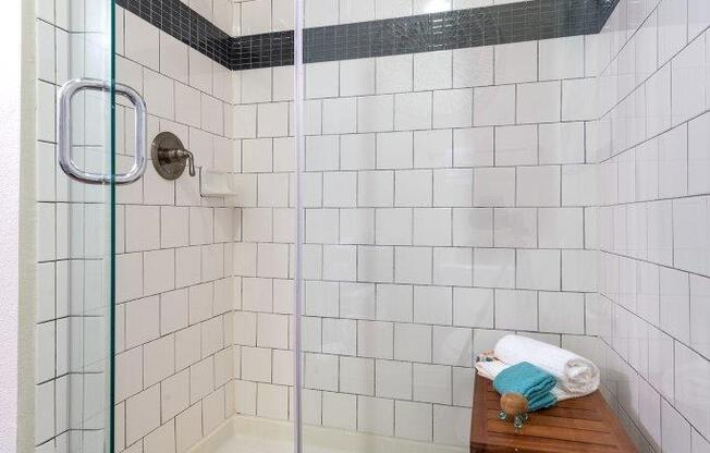 a bathroom with a shower and a wooden stool