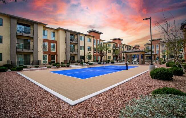 an outdoor pickleball court with apartments in the background