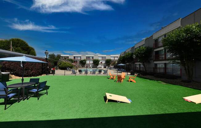 A playground with a green surface and various pieces of play equipment.