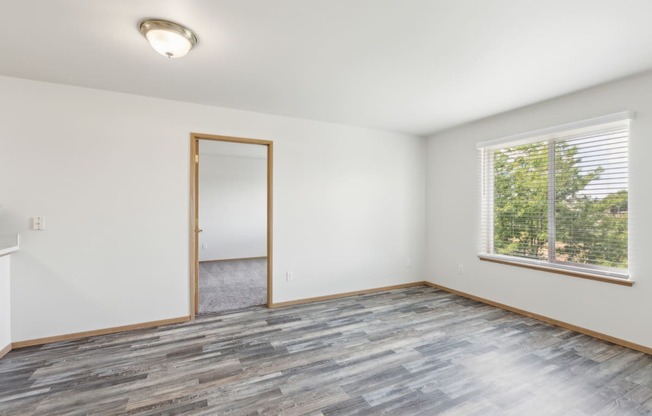 an empty living room with wood floors and a window