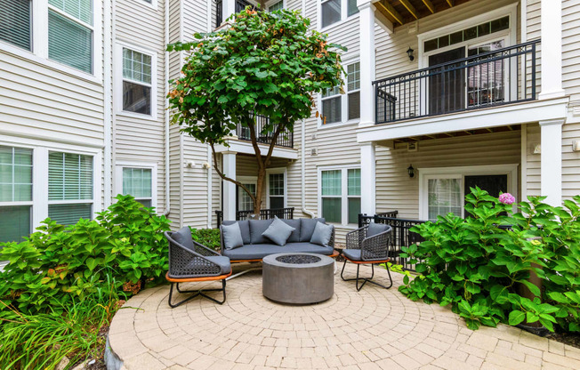 a patio with a firepit and seating area in front of an apartment building at Metro 303, Hempstead, 11550