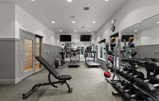A gym with a variety of equipment including weights and a bench.