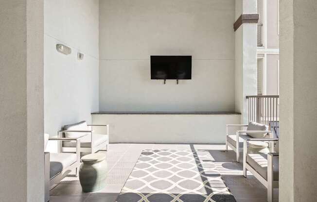 A living room with a television and white furniture.