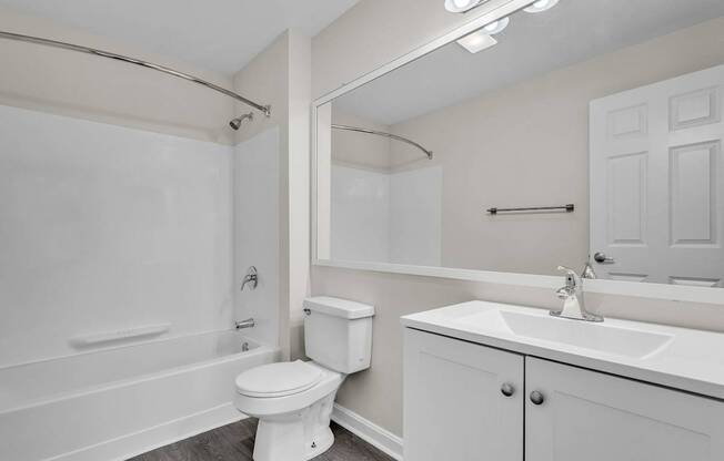 A white bathroom with a toilet, sink, and bathtub at the Ledges Apartments in Weymouth.
