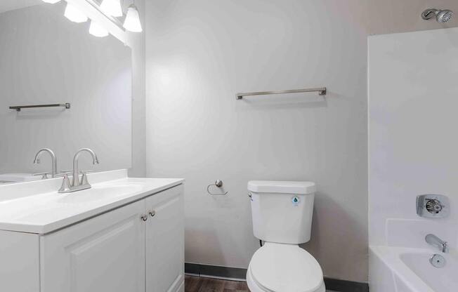 A white toilet with a blue sticker on the lid is in a bathroom with a white sink and a white cabinet.