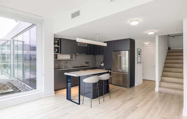 a kitchen with black cabinetry and a white counter top with three stools