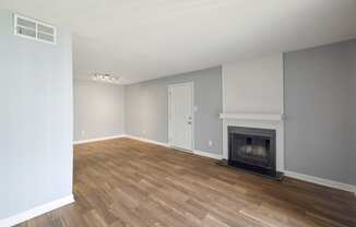 an empty living room with a fireplace and wooden floors  at Governors House, Alabama