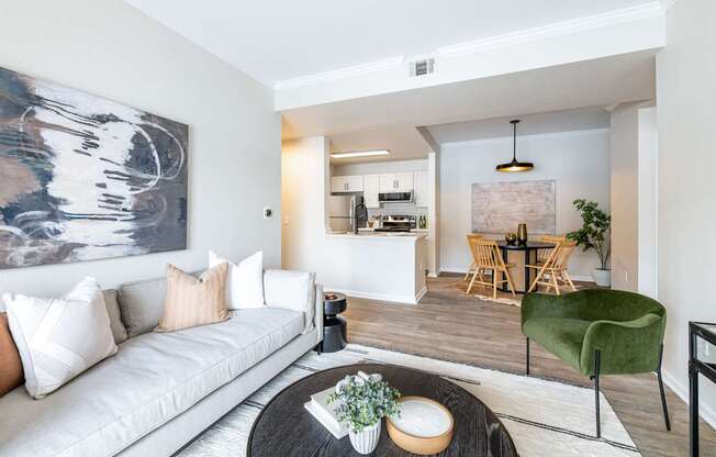 A modern living room with a white sofa and a large abstract painting on the wall.