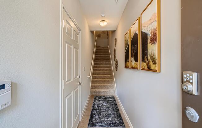 the entrance to a hallway with a staircase and a door leading up the stairs