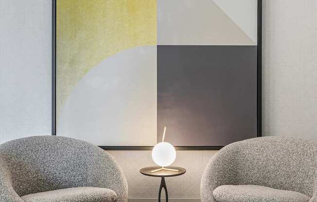 A modern living room with a grey sofa, a round table and a framed artwork on the wall.