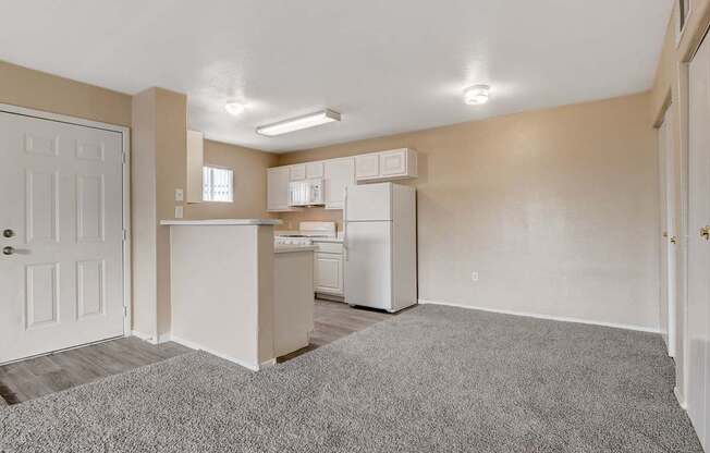A kitchen area with a white refrigerator and cabinets.