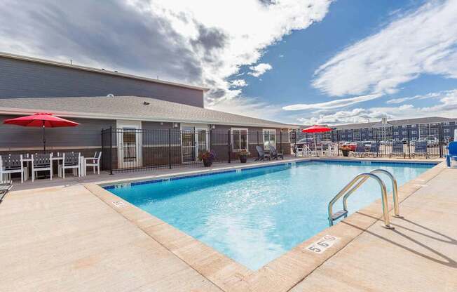 A pool area with a red umbrella and a metal fence.