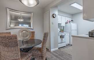 a dining area with a table and chairs and a kitchen in the background